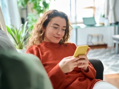 Woman looking at a smart phone while sitting on a lounge.